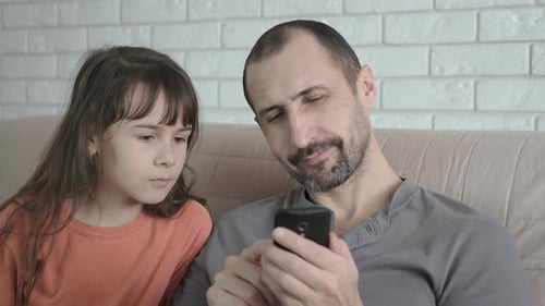 Father and Child React to Content on Phone