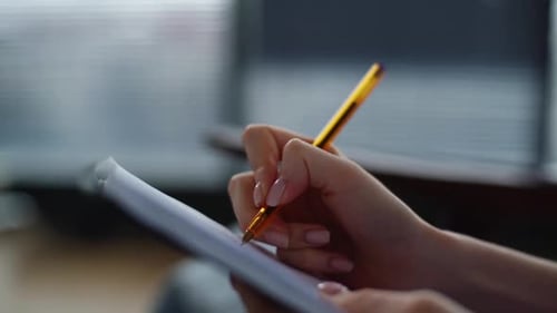 Woman Writing in Notebook Using Yellow Pen