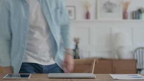 Man Opens Laptop at Desk Ready to Work