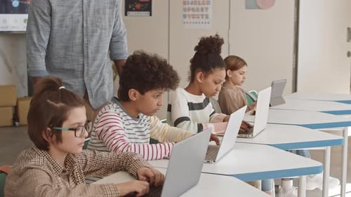 IT Teacher Helping Schoolchildren in Class
