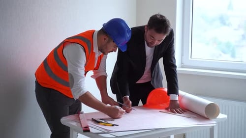 Construction Workers Reviewing Blueprints in Interior Space