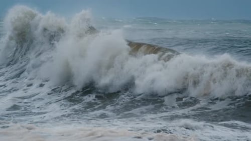 Big Wave with Foam and Dirt Breaks on the Shore During Strong Storm in the Atlantic Ocean