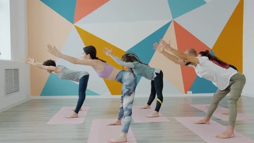 Group of Young People Training in Yoga Studio Concentrated on Bending Asana