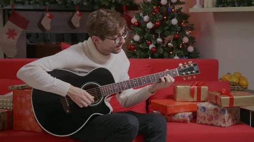 Man Plays Guitar at Christmas Time Indoors