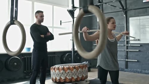 Woman Doing Barbell Torso Twists at Personal Workout with Coach