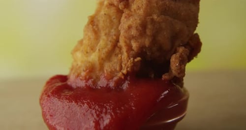 Dipping A Fried Chicken Leg Into A Bowl Of Ketchup On Green Background A Macro Shot