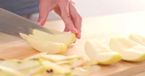 Hands Slicing an Apple on Wooden Board
