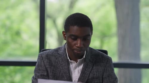 Front View Portrait of Serious Young African American Man Conferencing Online Showing Graph Talking