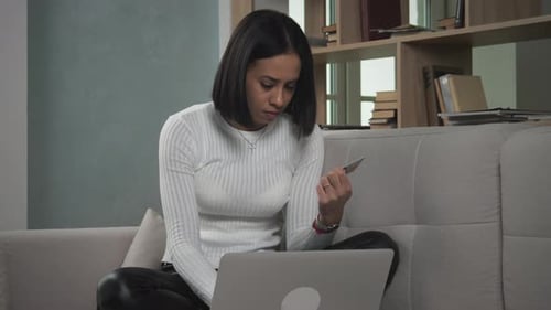 Woman Using Laptop with Credit Card on Sofa