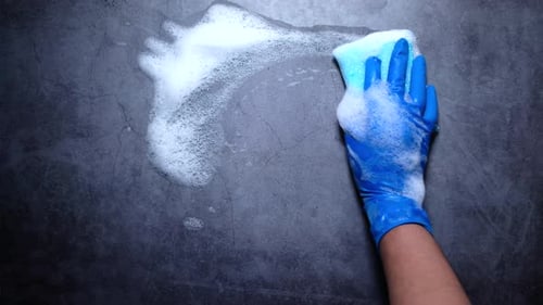 Hand in Blue Glove Cleaning Gray Surface