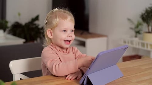 Happy Child Interacting with Tablet Device at Table