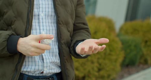 Man Applying Hand Sanitizer Outdoors for Health and Safety