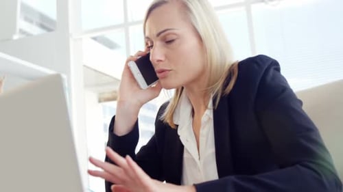 Businesswoman Talking on Phone While Working on Laptop