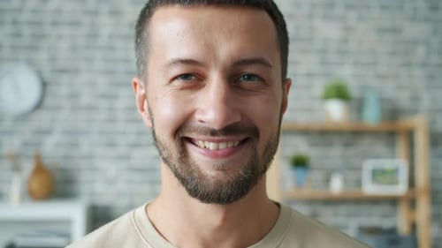 Close-up Portrait of Joyful Middle-aged Bearded Guy Smiling at Camera at Home