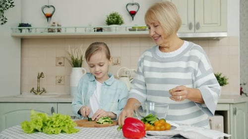 Grandmother and Girl Cut Vegetables in a Kitchen