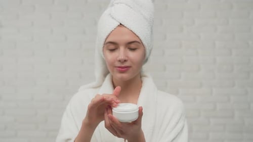 Woman in Bathrobe Putting Cream on Face