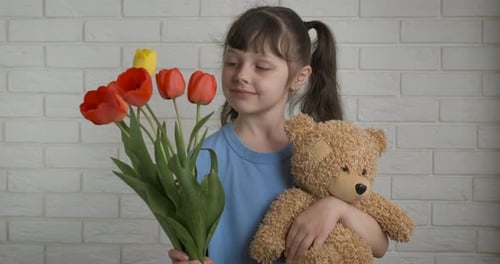 Little Girl Hugging Bear with Bouquet of Flowers