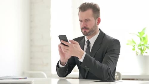 Frustrated Man in Suit Looking at Cell Phone