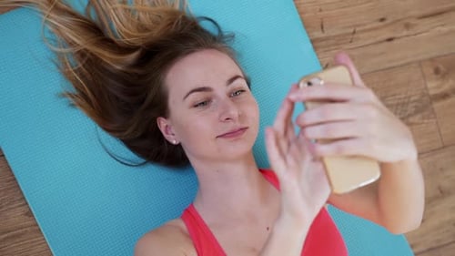 Woman Lying on Yoga Mat Using Smartphone