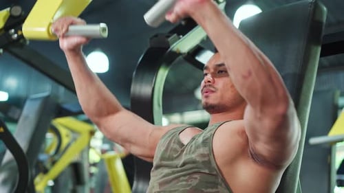 Asian Active fitness trainer man workout exercise by lifting weight machine in health club gym.