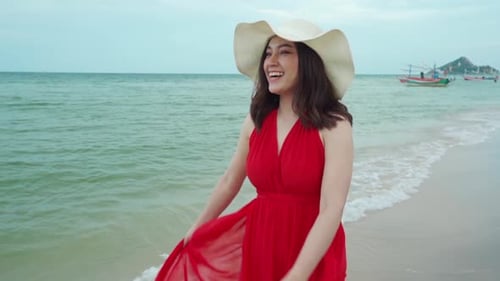 slow-motion of cheerful woman in red dress walking on the sea beach