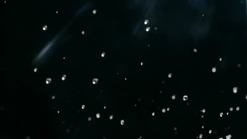 Water Droplets Rise in the Air Against Black Background. Slow Motion Water Splash