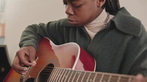 Young Adult Playing Acoustic Guitar Indoors