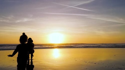 Mother and Child Silhouetted at Golden Sunset on Beach