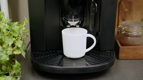 Coffee From Automatic Coffee Machine with Chromed Nozzle Into White Glass