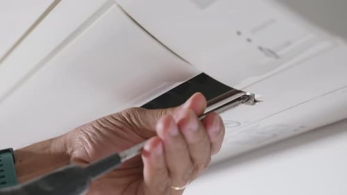 Professional technician screw with screwdriver placing back after clean filter air conditioner