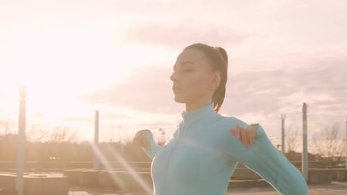 Woman Stretching on Rooftop at Sunrise