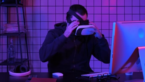Man Using Computer and VR Headset at Night