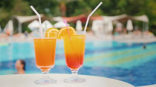 Zwei exotische Cocktails vor dem Hintergrund von Badetouristen im Pool in einem großen, komfortablen Hotel