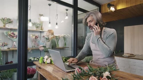 Florist Using Laptop and Talking on Phone