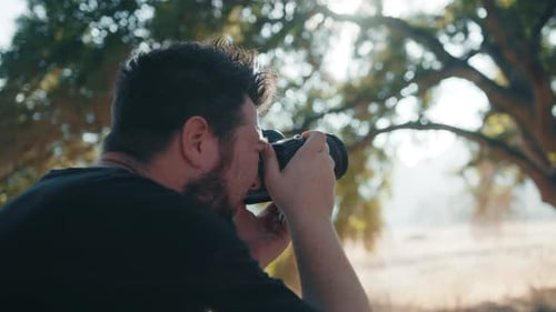 Back View of Professional Photographer Taking Pictures in Nature Park at Sunset