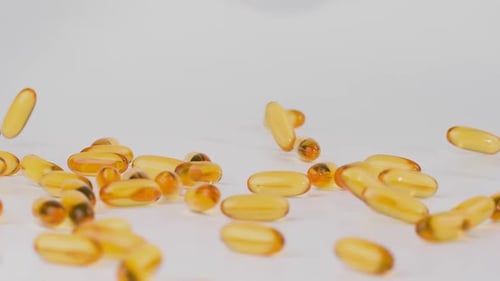 Gel Capsules Falling onto White Surface