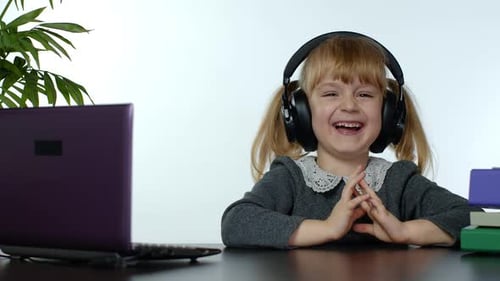 Happy Little Girl with Headphones Using Laptop