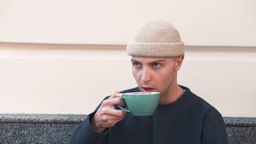 A Closeup Portrait of an Attractive Young Caucasian Man Holding Coffe Cup at Cafe