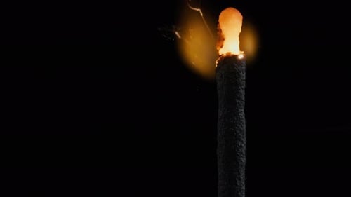 Burning Sparkler Emitting Golden Sparks on Black Backdrop