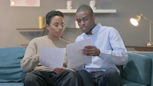 Couple Discussing Documents at Home on the Couch