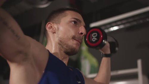 Sweaty Man Lifting Dumbbells at the Gym