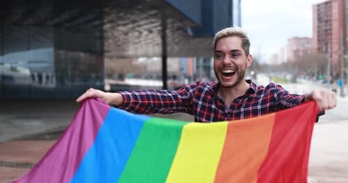 Gay man with makeup having fun holding lgbt rainbow flag outdoor