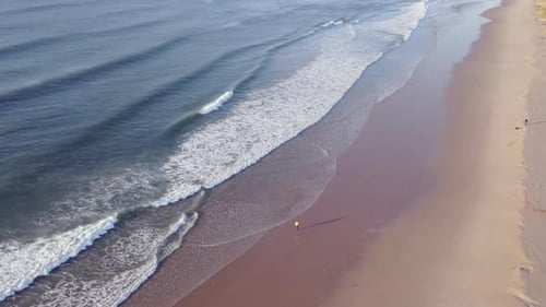Drone Ascending From Person Seen Walking Along Beach