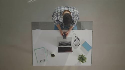 Young Adult Using a Cellphone at a Desk