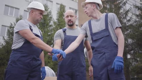 Tres jóvenes trabajadores caucásicos se ponen las manos, sacuden la cabeza y comienzan a trabajar