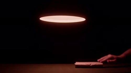 Hand Moves Brown Package on Table in the Dark