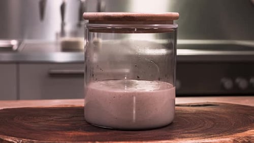 Sourdough Starter With Bubbles Rising In A Glass Jar For Baking During Fermentation. - zoom out