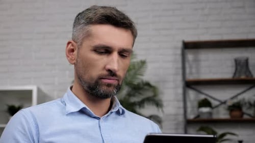 Close Up Man Stock Trader Broker Looks Tablet Analyzes Quotes on Stock Exchange