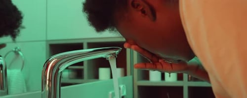 Mujer afroamericana lavándose la cara en el baño