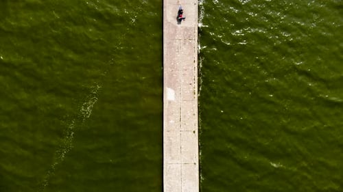 AÉREA: Voando sobre Stone Pier com pessoas deitadas nele em um dia ensolarado